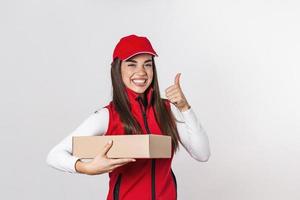 levering glimlachen vrouw in rood uniform geïsoleerd Aan wit achtergrond. vrouw in pet, t-shirt, jeans werken net zo koerier of handelaar Holding karton doos. ontvangen pakket. kopiëren ruimte voor advertentie foto