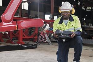 een Afrikaanse Amerikaans productie ingenieur test en controle robot arm in mechanisch fabricage fabriek, intelligent automatisch machines in industrieel bedrijf, en futuristische technologie innovatie. foto