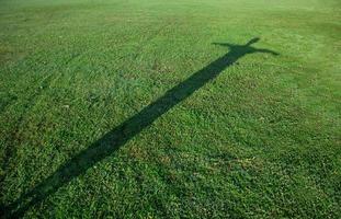 silhouet van Mens in kruis vorm Aan groen gras foto