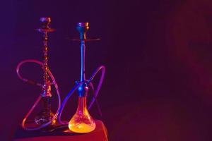 modern hookah, shisha Aan een zwart achtergrond met gekleurde verlichting en rook. plaats voor uw tekst foto