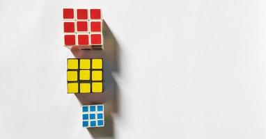 Jakarta, december 2022. drie rubik's kubussen van verschillend maten en kleuren geïsoleerd Aan wit achtergrond. vrij ruimte foto