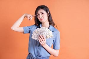jonge Aziatische zakenvrouw die zich voordeed op oranje achtergrond foto