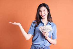 jonge Aziatische zakenvrouw die zich voordeed op oranje achtergrond foto