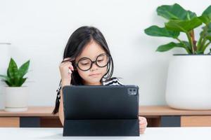 Aziatisch kind meisje leerling Wauw opgewonden Aan video telefoontje aan het leren naar aan het studeren online klasse of persoon leren van huis school- met tablet foto