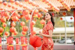 gelukkig Chinese nieuw jaar. mooi Aziatisch vrouw vervelend traditioneel cheongsam qipao jurk op zoek zelfverzekerd Holding lantaarn terwijl bezoekende de Chinese boeddhistisch tempel foto