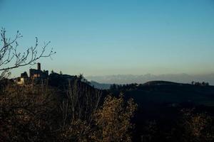 de kasteel van serralunga d'alba ondergedompeld in de landschap van de piemontese langhe, in de buurt alba, met de kleuren van de herfst seizoen foto