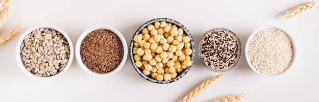 quinoa, sesam, kikkererwten, zonnebloem zaden en vlas zaden in de kommen. top visie. web banier foto