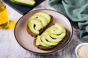 bruschetta met avocado en sesam zaden Aan rogge brood Aan een bord. gezond voedsel. foto
