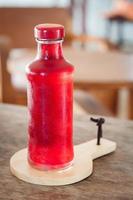 fles rode frisdrank op een houten dienblad foto