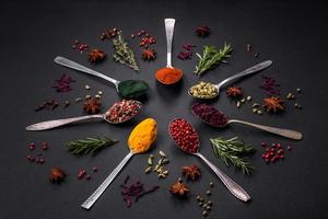 variatie van specerijen in metaal lepels paprika, kurkuma, kardemom, een mengsel van piment, tijm en rozemarijn foto