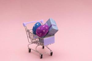 Pasen eieren kleurrijk in de boodschappen doen kar Aan roze achtergrond. kopiëren ruimte voor tekst. foto