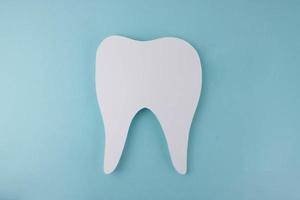 wit papier tand Aan een blauw achtergrond. de concept van tandarts dag, tandarts dag foto