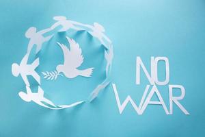 Daar is Nee oorlog. mensen besnoeiing uit van papier Aan een blauw achtergrond beschermen de duif van vrede.de concept van de wereld vrede dag foto