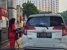 Jakarta, Indonesië in juli 2022. een vrouw gas- station begeleider tankt een wit auto. foto