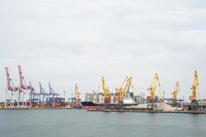 zeehaven waar groot kranen zijn geladen containers Aan lading schepen foto