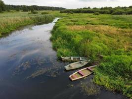 drie oud boten Aan een klein rivier- afgemeerd naar de oever, top visie. foto