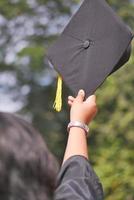 leerling houden hoeden in hand- gedurende aanvang succes Aan geel achtergrond foto