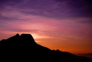 romantisch Purper en oranje zonsondergang over- de hoog tatra bergen met dicht de nevel en lang zon stralen. levendig en kleurrijk zonsopkomst van de piek. trekking gedurende gouden uur in de Woud. foto