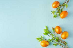 gelukkig Pasen. glanzende gouden eieren en groene wilgenknoppen op blauwe achtergrond. foto