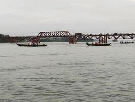 bezig mensen kruispunt de hoornvlies rivier- door boot en de spoorweg brug in chittagong, bangladesh. kalerghat spoor annex weg brug was gebouwd over honderd jaren geleden door de vroeger Brits regime. foto