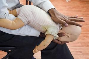 Mens het uitvoeren van cpr Aan baby opleiding pop dummy met een hand- compressie. eerste steun opleiding - cardiopulmonaal reanimatie. eerste steun Cursus Aan cpr pop, cpr eerste steun opleiding concept foto
