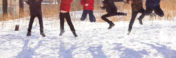 groep van vrolijk kinderen jumping in de sneeuw in winter foto