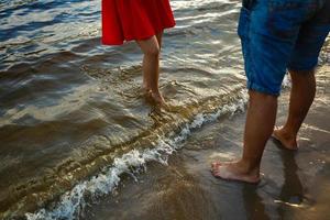 zomer paar Bij zonsondergang Aan strand. romantisch jong paar genieten van zon, zonneschijn, romance en liefde door de zee. paar Aan zomer vakantie reizen vakantie. foto