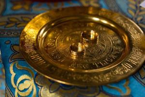 gouden bruiloft ringen Aan metaal bord in kerk met heilig water. bruiloft traditioneel ceremonie. ruimte voor tekst foto