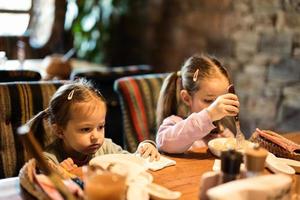 familie hebben een maaltijd samen in authentiek oekraïens restaurant. meisjes kinderen eten knoedels. foto