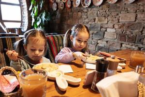 familie hebben een maaltijd samen in authentiek oekraïens restaurant. meisjes kinderen eten knoedels. foto
