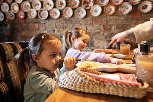 familie hebben een maaltijd samen in authentiek oekraïens restaurant. meisjes kinderen eten knoedels. foto