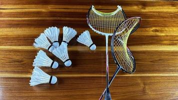 dichtbij omhoog van gebroken badminton rackets en wit badminton shuttle hanen Aan bruin houten achtergrond foto