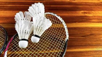 dichtbij omhoog van gebroken badminton rackets en wit badminton shuttle hanen Aan bruin houten achtergrond foto