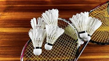 dichtbij omhoog van gebroken badminton rackets en wit badminton shuttle hanen Aan bruin houten achtergrond foto