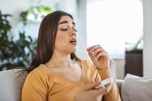 jong vrouw Holding zelf testen zelf beheerd wattenstaafje en medisch buis voor coronavirus covid19, voordat wezen zelf getest Bij huis foto