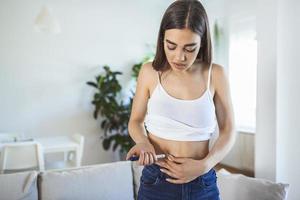 jong diabetes vrouw maakt een insuline injectie met insuline pen Bij huis. diabetisch levensstijl foto