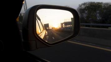 vleugel spiegel visie van auto Aan de asfalt weg. met reflecties van andere auto's voering de terug in verkeer. milieu in de avond of ochtend- tijd. foto