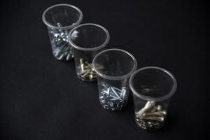 bouw bouten en schroeven in plastic cups Aan een zwart achtergrond. bouw accessoires. foto