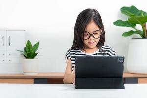 Aziatisch kind meisje leerling Wauw opgewonden Aan video telefoontje aan het leren naar aan het studeren online klasse of persoon leren van huis school- met tablet foto