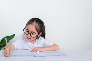 portret van weinig leerling schrijven Bij bureau in leerling meisje studie aan het doen test in primair school. kinderen schrijven aantekeningen in klas. onderwijs kennis concept foto