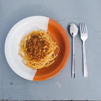 gezond bord van Italiaans spaghetti bekroond met een smakelijk tomaat en grond rundvlees bolognese saus en vers basilicum Aan een grijs tafel foto