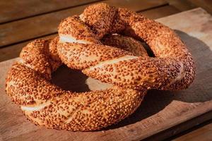 vers gebakken bagel met sesam zaden Aan een houten tafel in de stralen van zonlicht. Turks bagel simit detailopname, vers gebakjes voor ontbijt. foto