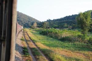 buiten venster spoorweg sporen in de platteland met zonsondergang lucht visie en berg Woud foto