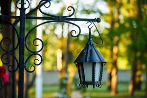 oud verroest lantaarn Aan een houten huis en bloemen foto