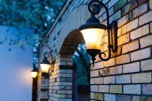 lantaarn Aan steen muur van oud stad, vervagen veel lampen Aan pijler foto