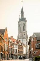 hoog middeleeuws klok toren stijgende lijn over- de straat met oud Europese huizen, doornik, Waals gemeente, belgie foto
