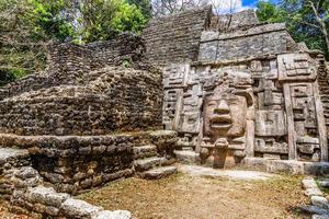 oud oude steen mayan pre-columbiaans beschaving piramide met gesneden gezicht en ornament verborgen in de Woud, lamanai archeologisch plaats, oranje wandelen wijk, Belize foto