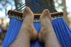 man's voeten aan het liegen Aan de bed Aan vakantie foto