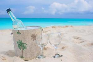 fles van wijn en twee bril Aan zanderig strand foto