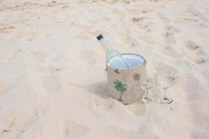 fles van wijn en twee bril Aan zanderig strand foto